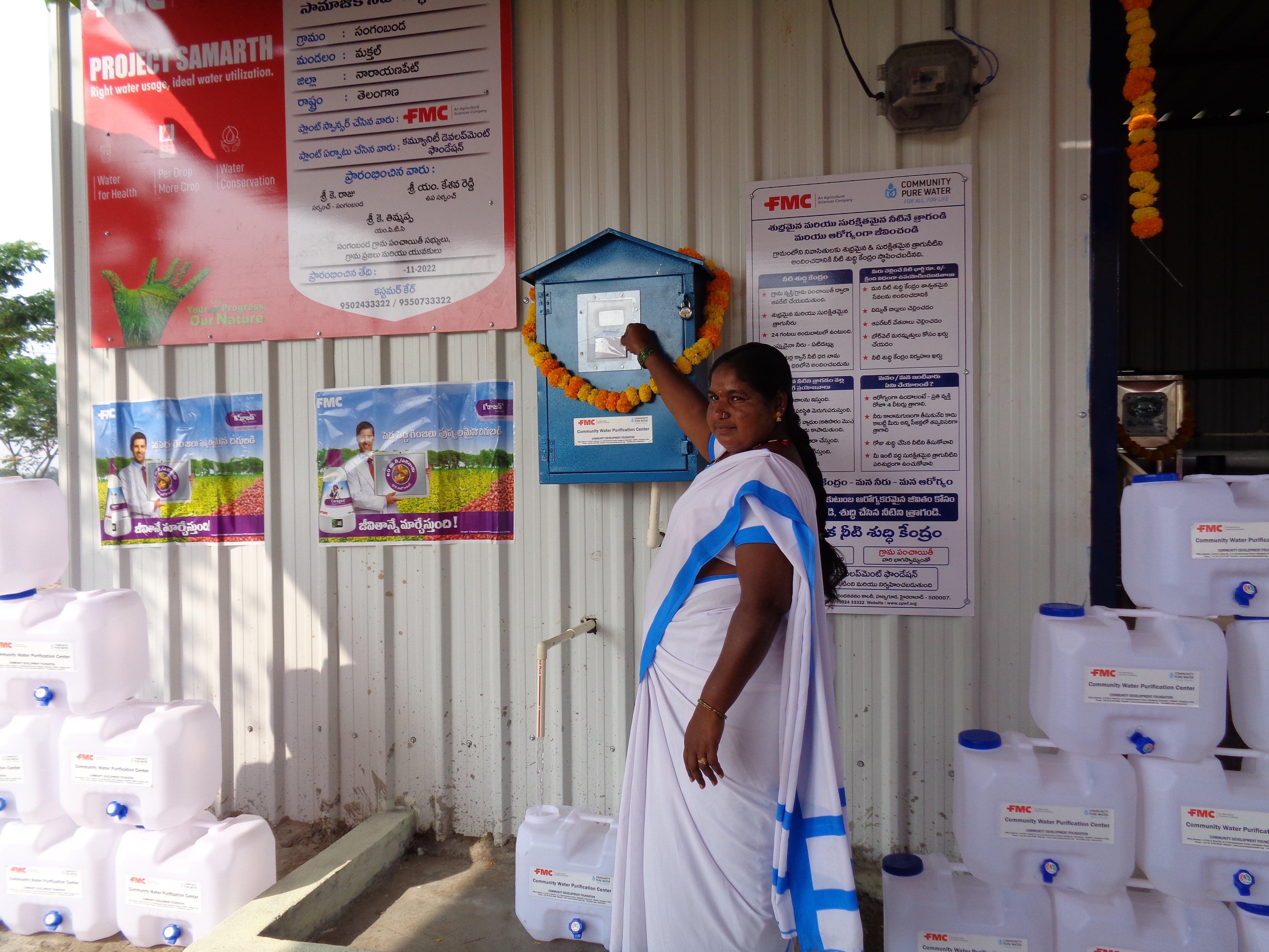 Resident of Narayanpet, India visits the village's newly installed water filtration plant, courtesy of FMC India. She is wearing a white and blue sari as she smiles at the camera. The new filtration plant in Naraynanpath is one of two water filtration plants in India's Telangana state that were recently inaugurated by FMC India and local dignitaries. 