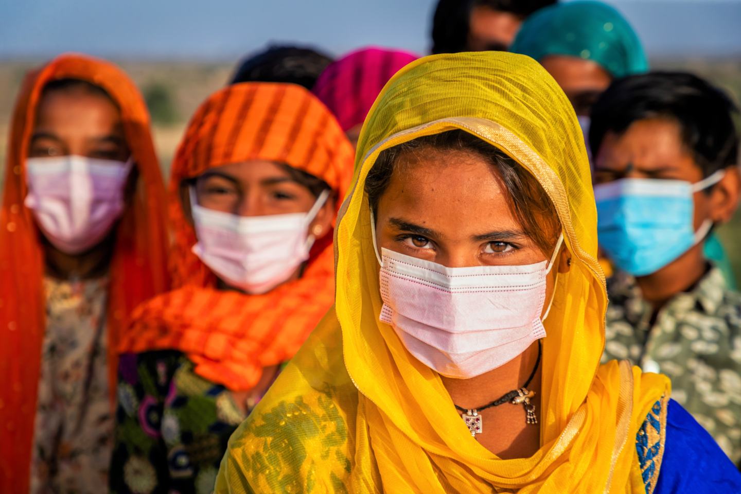 Young Indian girls wearing medical masks stand in the Thar Desert. Sustainability innovation.