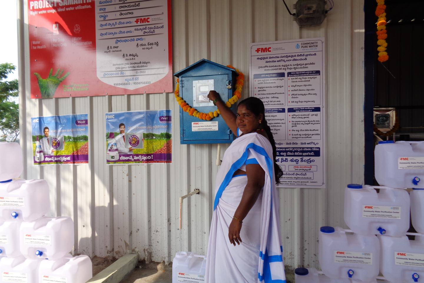 Resident of Narayanpet, India visits the village's newly installed water filtration plant, courtesy of FMC India. She is wearing a white and blue sari as she smiles at the camera. The new filtration plant in Naraynanpath is one of two water filtration plants in India's Telangana state that were recently inaugurated by FMC India and local dignitaries. 
