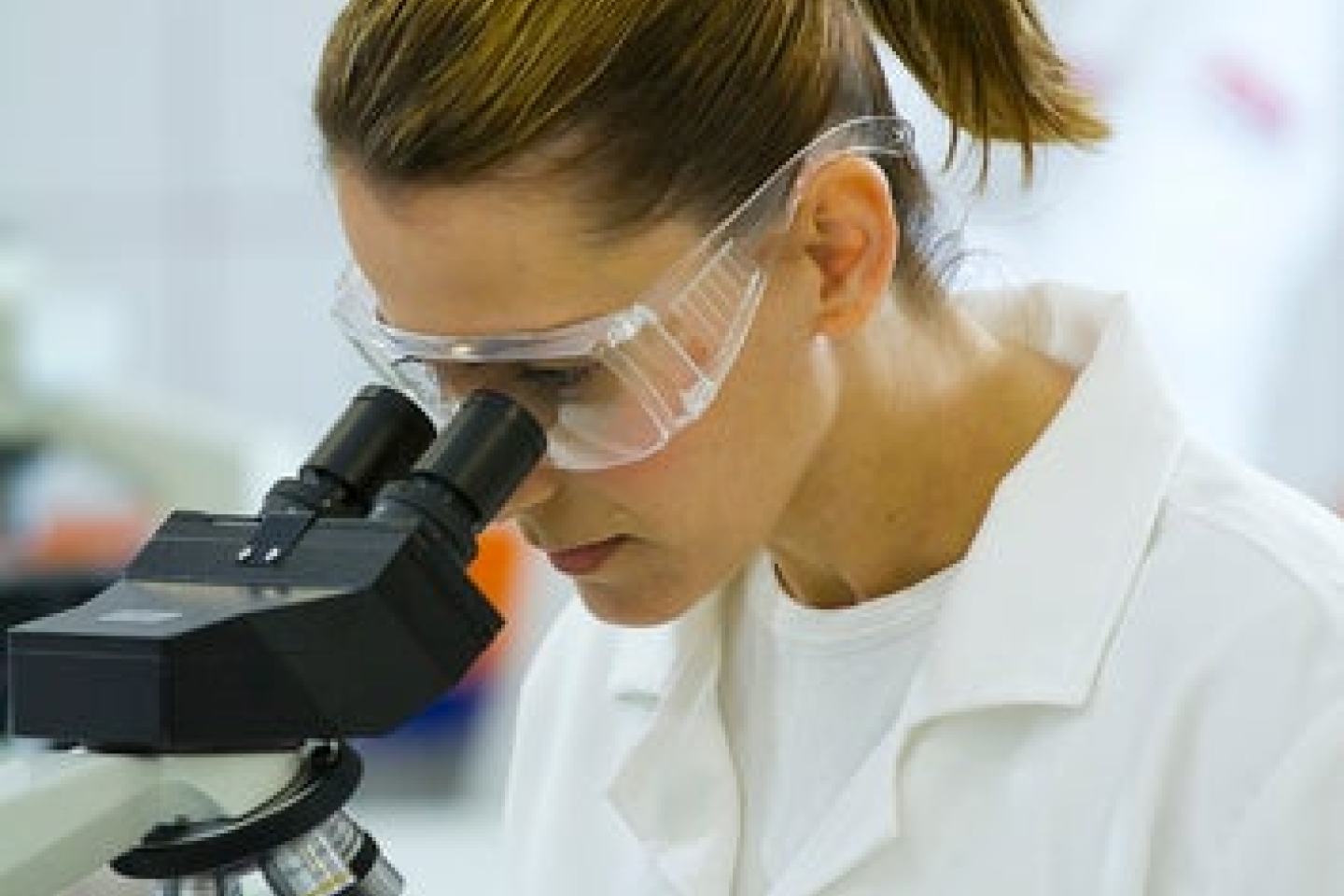 Female FMC scientist looks through microscope. Sustainability, agritech, agrochem, innovation.